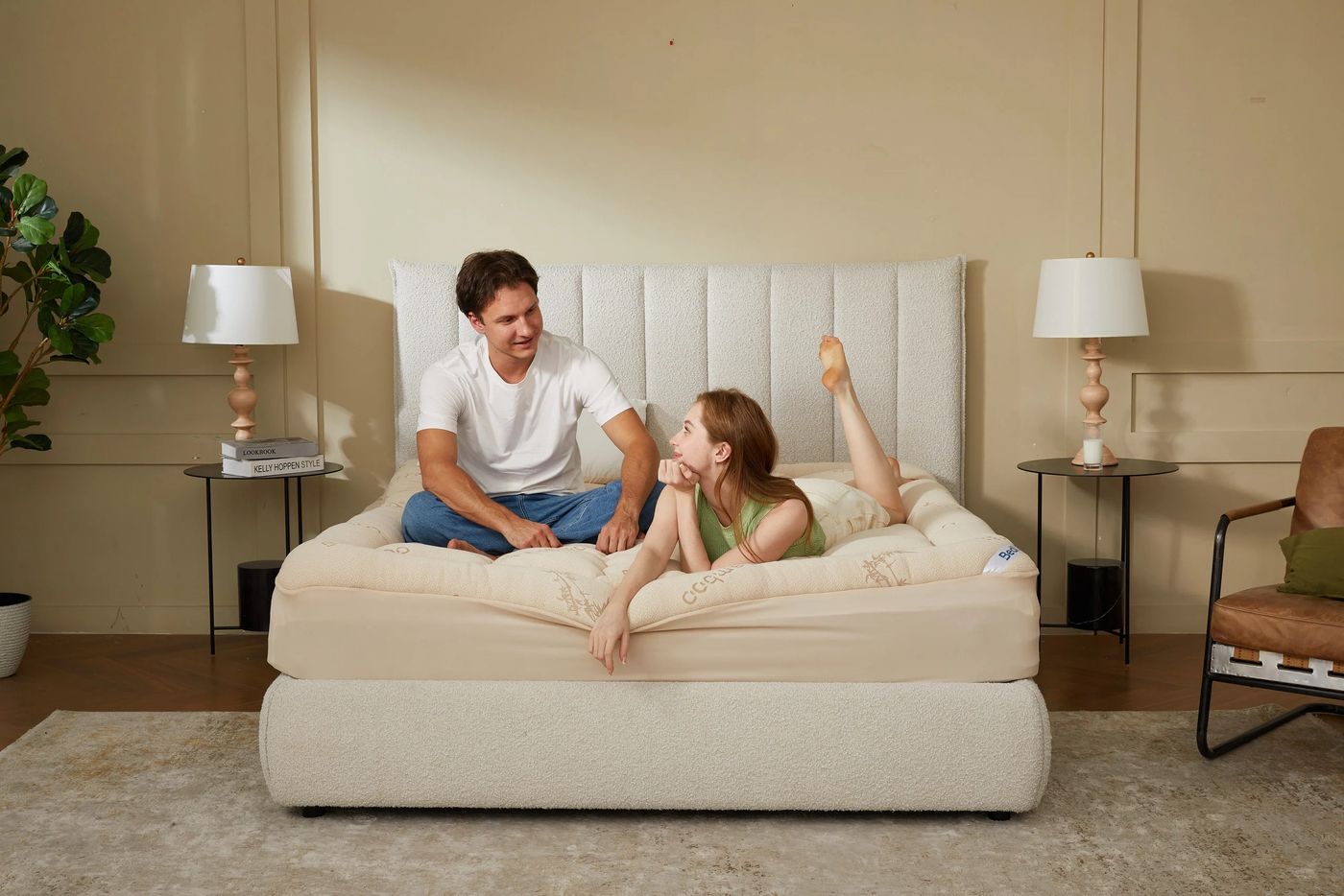 Pareja sentada en la cama sobre un topper beige